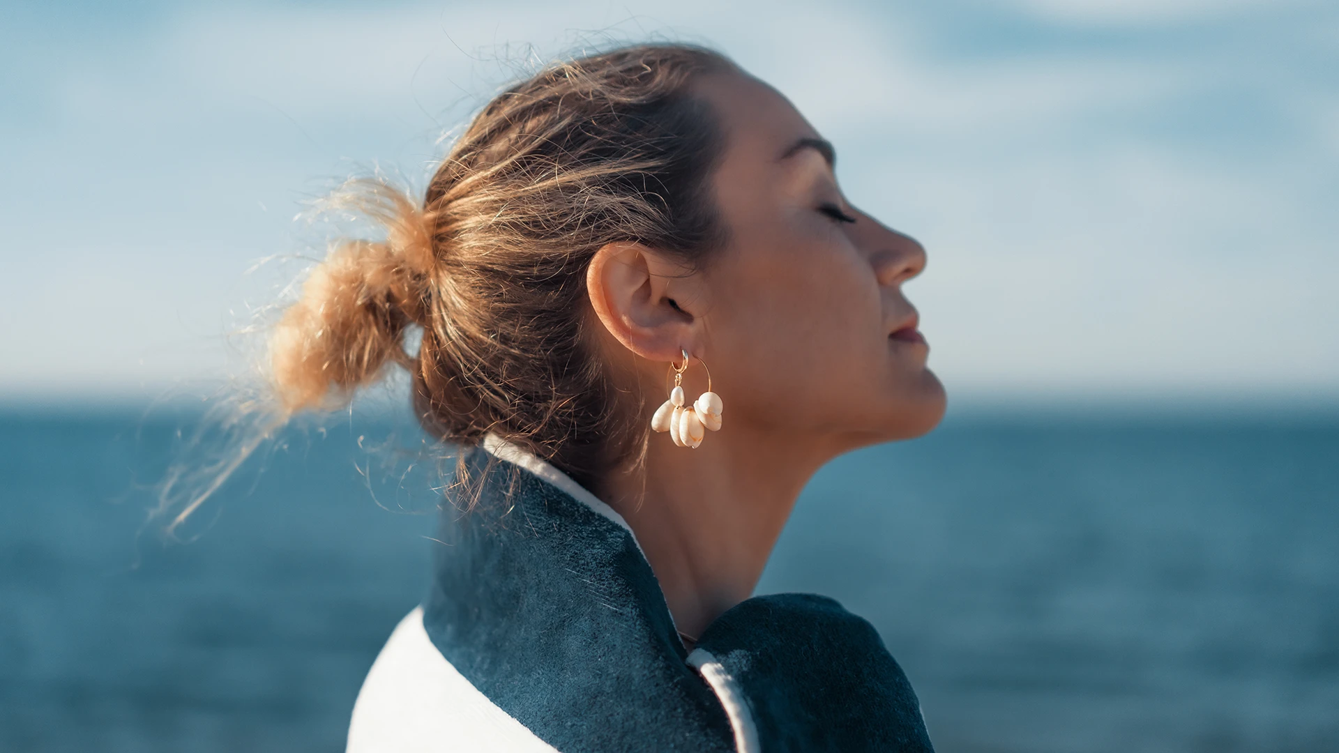 Une femme pratique la sophrologie à la mer en vivant pleinement l'instant présent. Espace zen de DENADDA.